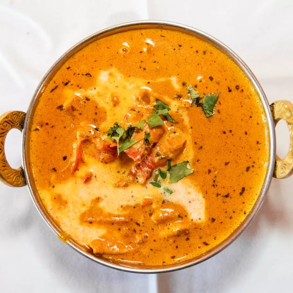 A close-up of Masala Indian Cuisine's butter chicken, garnished with fresh cilantro in a metal bowl.